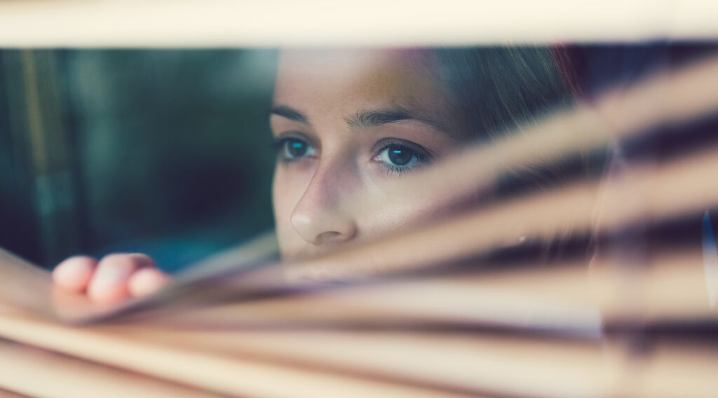 Photo of an unhappy woman looking through the window