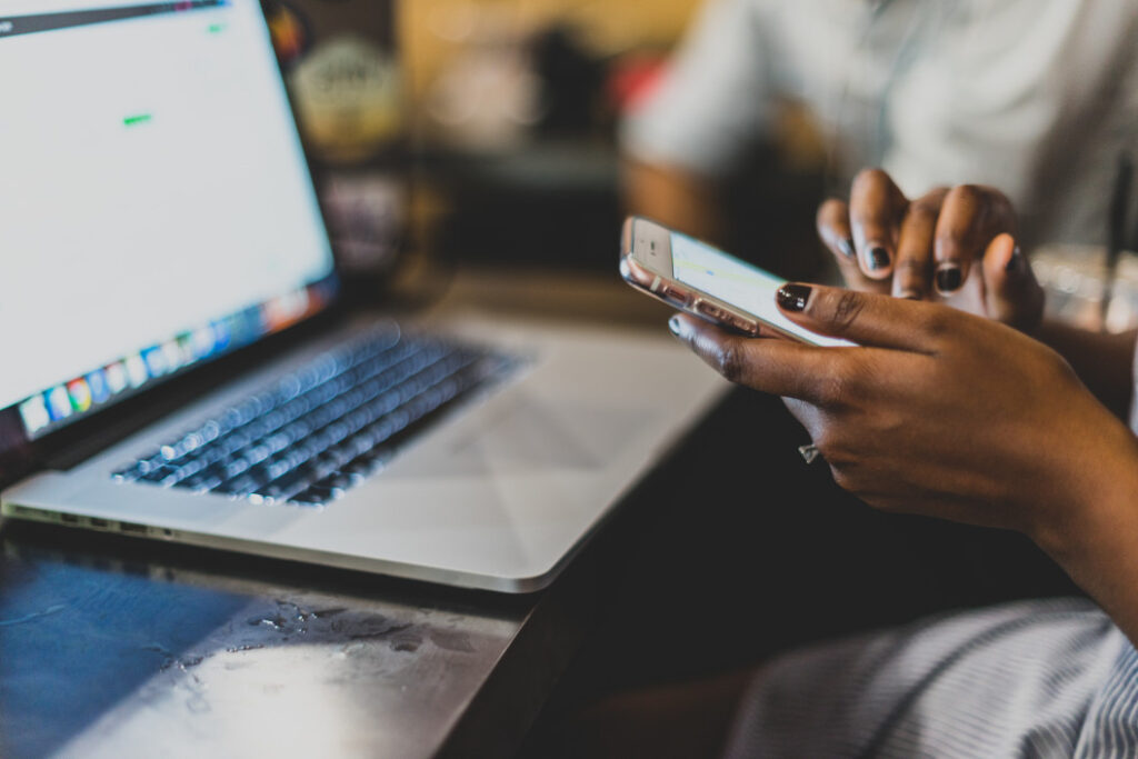 Photo of a woman multitasking with a laptop and a phone, illustrating integrated digital marketing