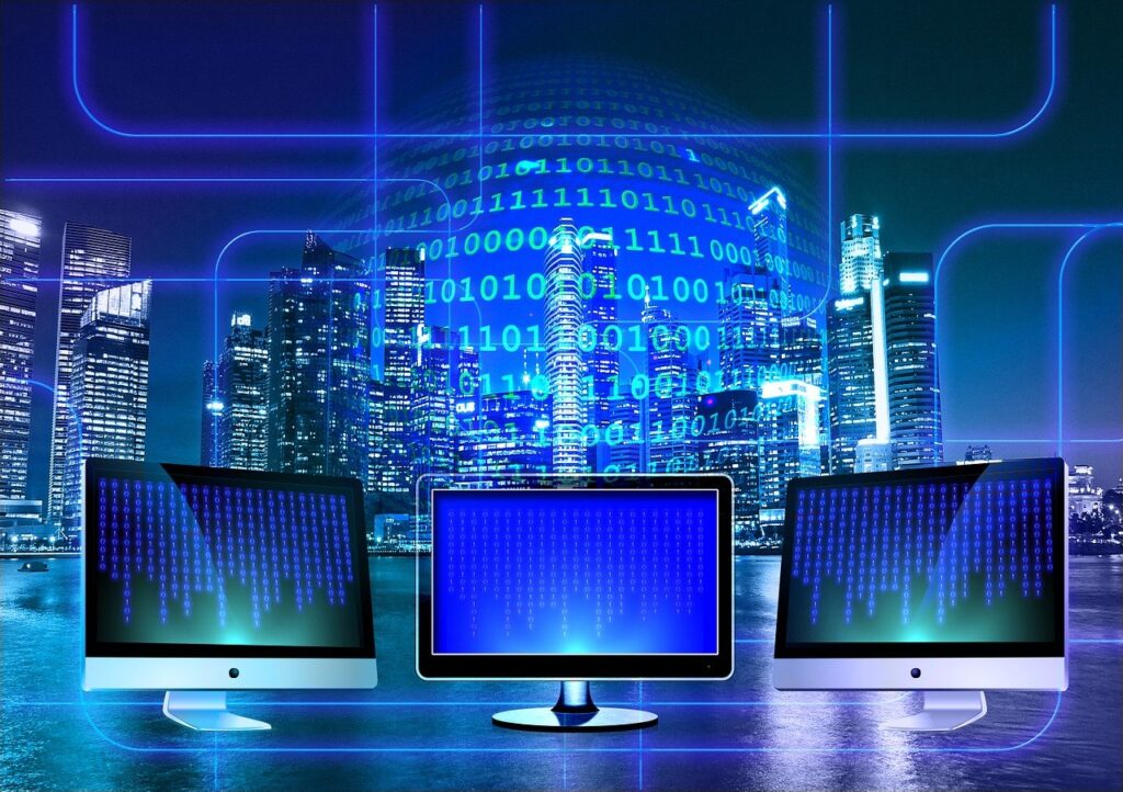 Three computer screens with a backdrop of a stylized and digitized city skyline