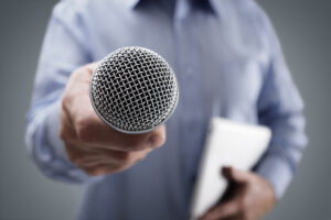 Hand holding a microphone conducting a business interview to emphasize how to utilize data-driven PR to tell better stories