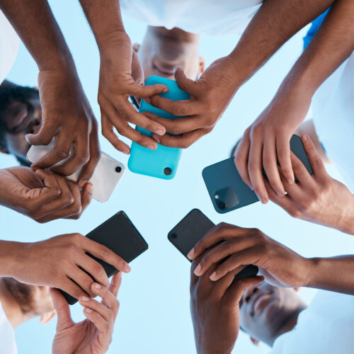 People in a huddle or circle holding their mobile phone. Digital advocacy.