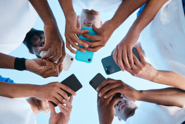 People in a huddle or circle holding their mobile phone. Digital advocacy.
