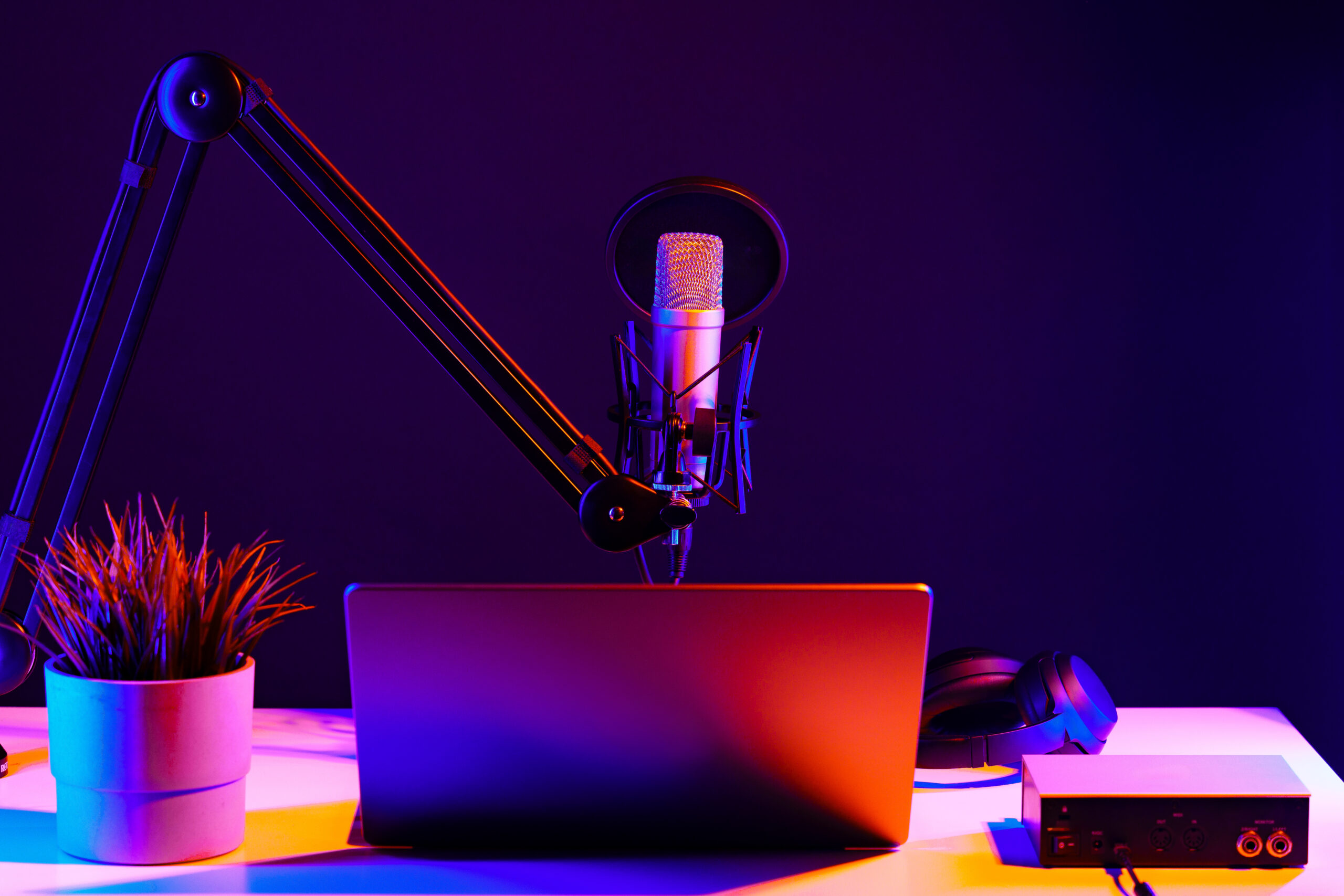 Professional microphone and laptop in recording studio in neon light